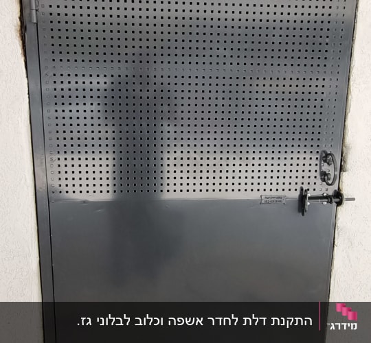 דלת ברזל אפורה מותקנת בקיר, כוללת חלק עליון מנוקב ובריח נעילה